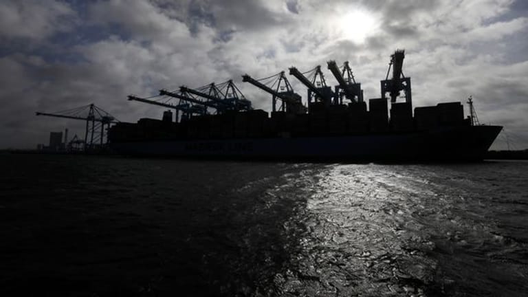 Die Silhouette eines Containerschiffes zeichnet sich im Hafen von Rotterdam gegen die Sonne ab.