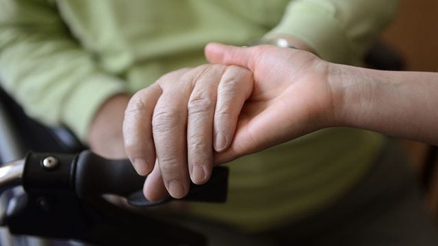 Eine Pflegerin hält in einem Pflegeheim die Hand einer Person (Symbolbild): Bewohner von Pflegeheimen, die Corona-Fälle haben, dürfen keinen Besuch mehr bekommen. Eine Pflegerin hält in einem Pflegeheim die Hand einer Person (Symbolbild): Bewohner von Pflegeheimen, die Corona-Fälle haben, dürfen keinen Besuch mehr bekommen.