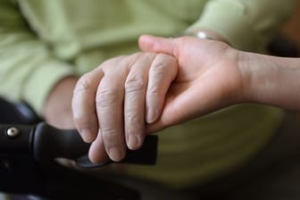 Eine Pflegerin hält in einem Pflegeheim die Hand einer Person (Symbolbild): Bewohner von Pflegeheimen, die Corona-Fälle haben, dürfen keinen Besuch mehr bekommen.