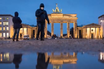 Nach dem Regen spiegelt sich das Brandenburger Tor in einer Pfütze: Bei einem möglichen "echten" Lockdown werden hier noch nicht mal mehr Touristen zu sehen sein.