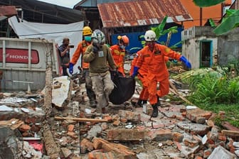 Rettungskräfte tragen in Mamuju einen Leichensack aus den Trümmern.