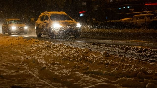 Autos sind in Freiburg im dichten Schneetreiben unterwegs.
