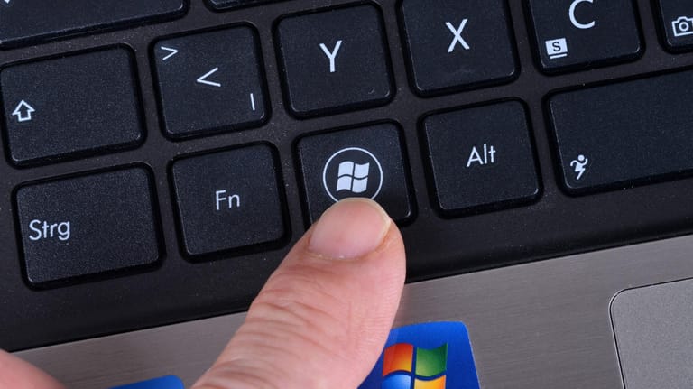 Jemand zeigt auf die Windows-Taste auf einer Computertastatur: Mit einer Kombination können Nutzer schnell zum Desktop wechseln.