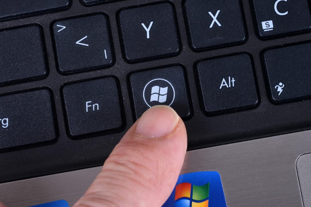 Jemand zeigt auf die Windows-Taste auf einer Computertastatur: Mit einer Kombination können Nutzer schnell zum Desktop wechseln.
