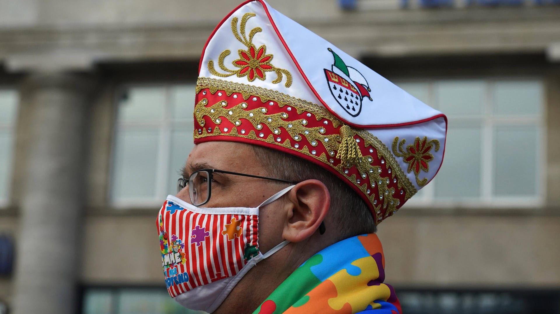 Ein Karnevalist trägt einen bunten Mundschutz bei der Sessionseröffnung am 11.11. in Köln: Die Traditionskorps hoffen nun auf die nächste Session.