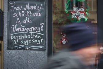 "Frau Merkel schickt uns in die Verlängerung! Durchhalten ist angesagt!" steht auf einer Tafel neben einem geschlossenen Geschäft im hessischen Friedberg.