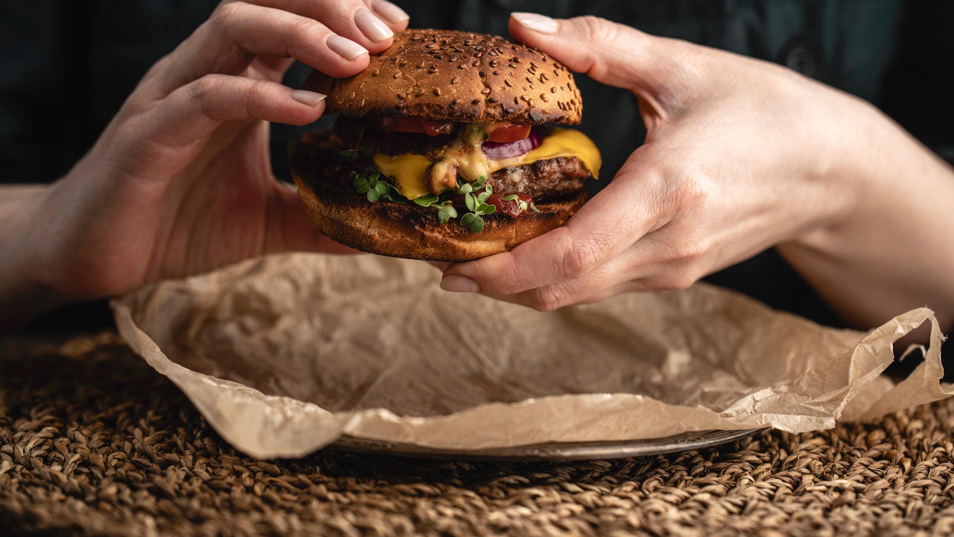 Eine Frau isst einen Burger (Symbolbild): Weil ein Imbiss seine Eröffnung feierte, kam es zu einem größeren Menschenandrang.