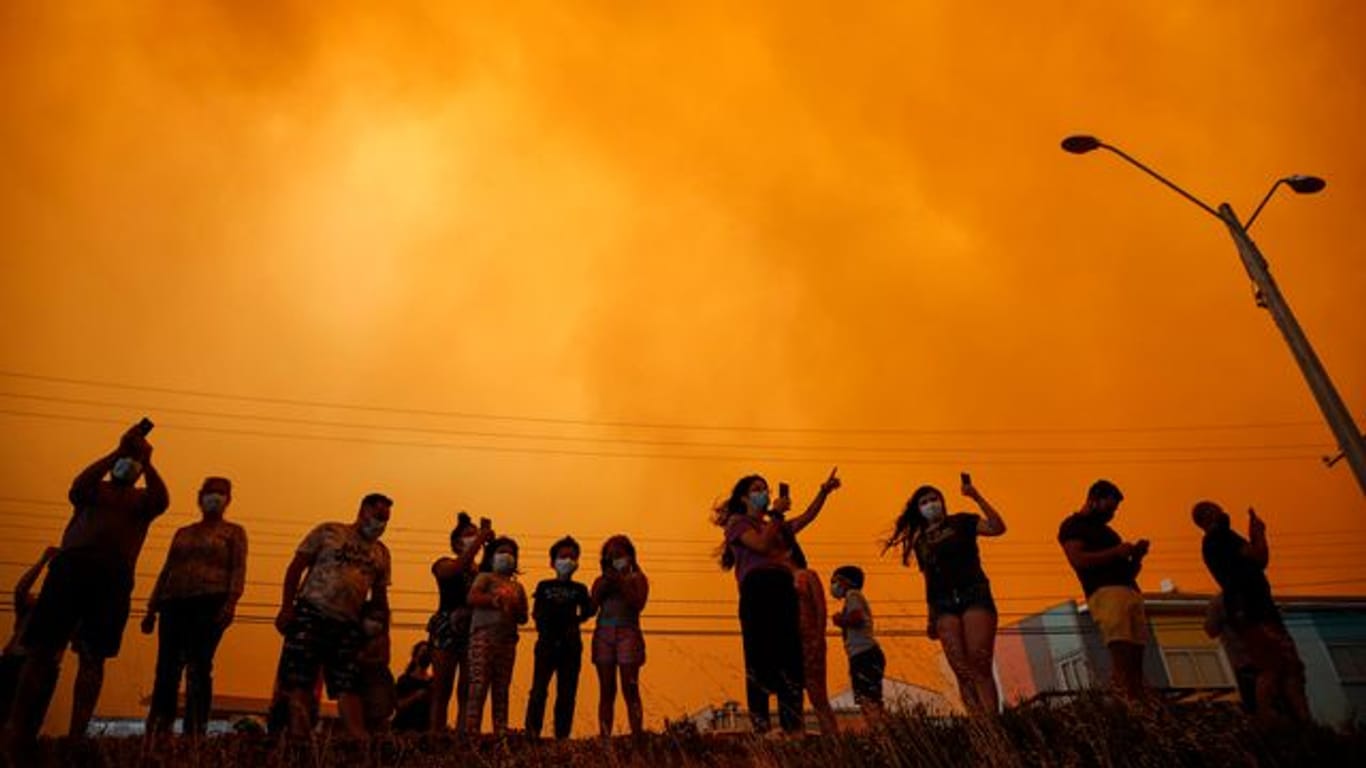 Anwohner beobachten in Quilpué die durch den Waldbrand ausgelösten Rauchwolken am Himmel.