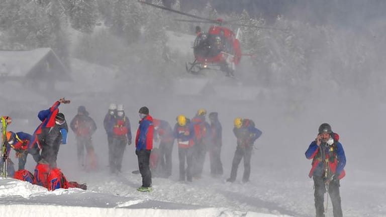 Ein Helikopter landet hinter Helfern der Bergrettung.