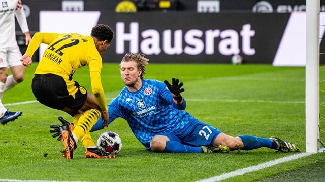 Der Mainzer Torwart Robin Zentner (r) sptitzelt Dortmunds Jude Bellingham den Ball vom Fuß.