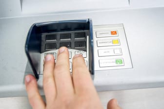 Eine Person gibt ihre PIN ein (Symbolbild): In Deutschland werden immer seltener Daten am Bankautomaten gestohlen.