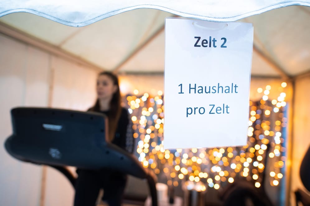 Eine Frau trainiert auf einem Laufband in einem Fitness-Zelt, ein Schild weist auf die Einschränkungen hin. Der Lockdown in Deutschland wird wohl noch verlängert werden. Heute tagen Bund und Länder.