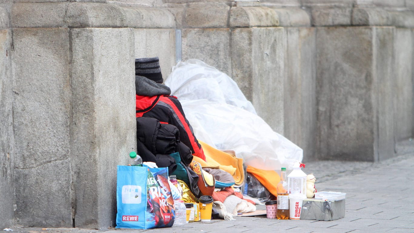 Obdachloser Mann liegt mit seinem Hab und Gut an einer Mauer (Symbolbild): In Mainz gab es in diesem Winter bisher drei Todesfälle von Wohnungslosen.
