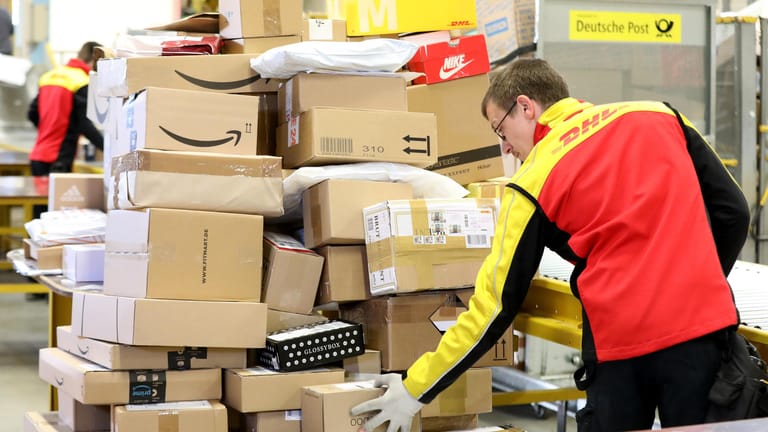 Ein DHL-Mitarbeiter sortiert Pakete (Archivbild): Die Corona-Pandemie hat den Paket-Boom weiter angeheizt.