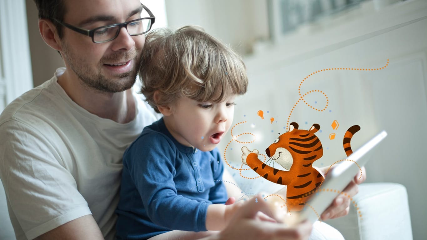 Vater und Sohn schauen auf ein Tablet (Symbolbild): Die App "TigerBooks" bietet Kindern digitalen Zugang zu ihren Helden.