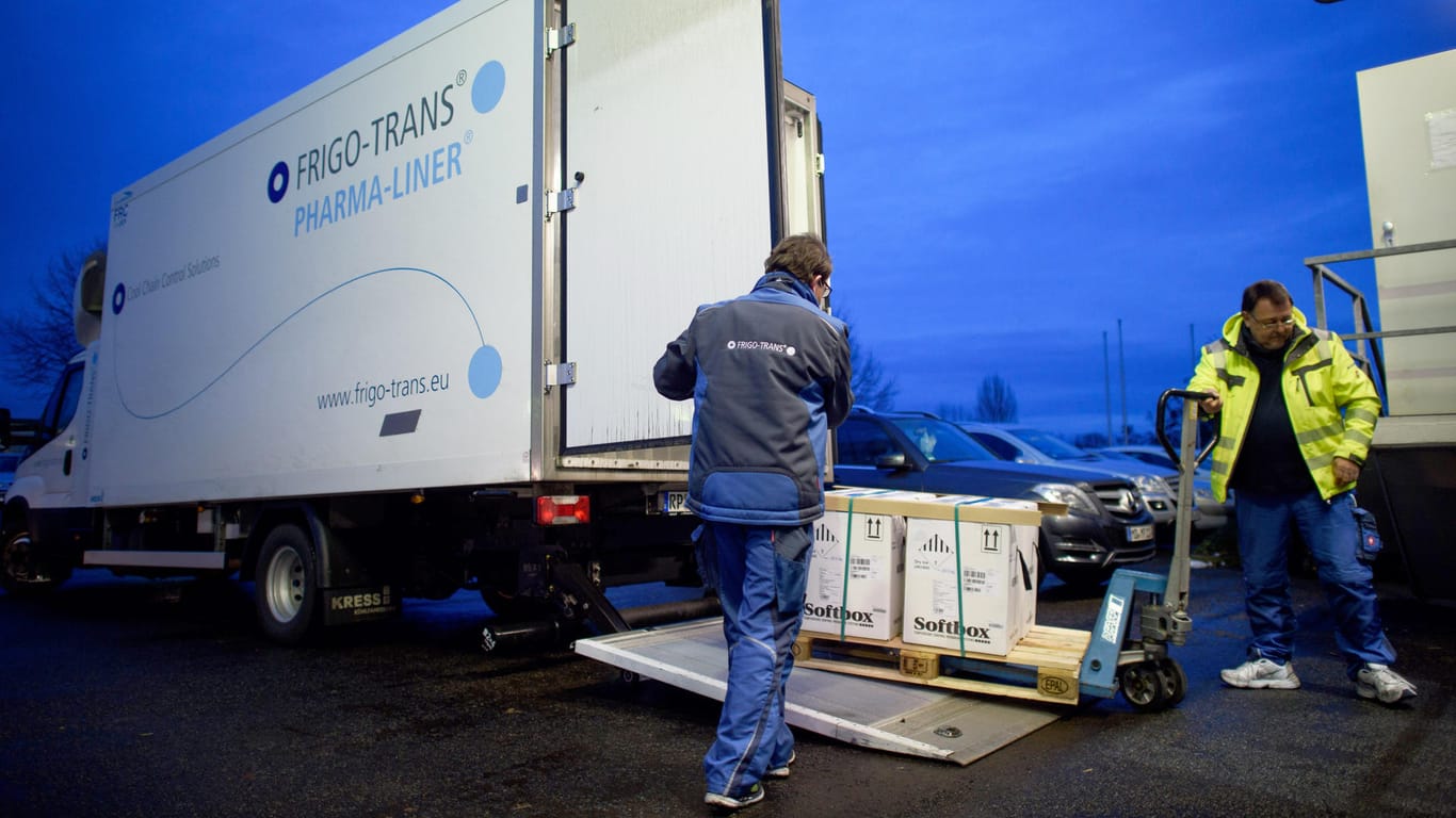 Sachsen-Anhalt, Irxleben: Fahrer eines Kühllastwagens entladen in einem Logistikzentrum Kisten mit Impfdosen von Biontech/Pfizer.