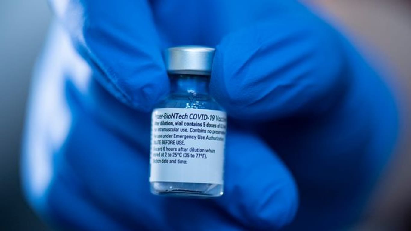 Eine Apothekerin hält eine Ampulle des Corona-Impfstoffs von Pfizer-Biontech in der Hand.