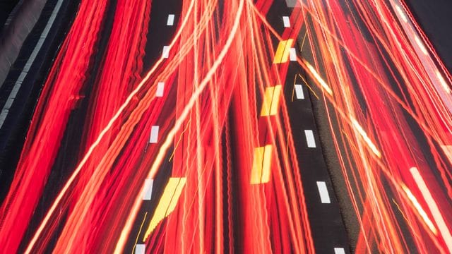 Die Scheinwerfer vorbeifahrender Fahrzeuge ziehen auf einer Autobahn ihre Lichtspuren durch die hereinbrechende Dunkelheit (Aufnahme mit Langzeitbelichtung). Die Scheinwerfer vorbeifahrender Fahrzeuge ziehen auf einer Autobahn ihre Lichtspuren durch die hereinbrechende Dunkelheit (Aufnahme mit Langzeitbelichtung).