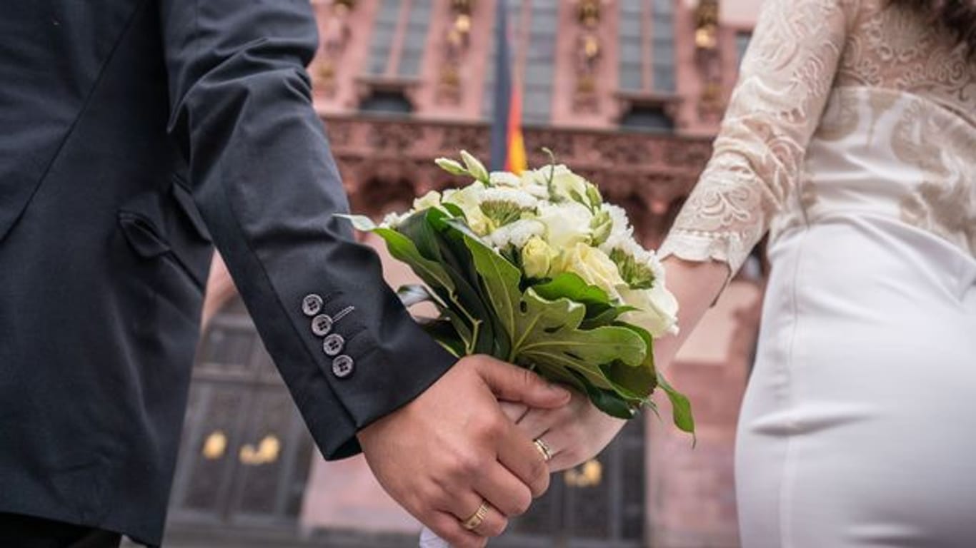 Ein Brautpaar steht nach der standesamtlichen Trauung auf dem Römerberg in Frankfurt.