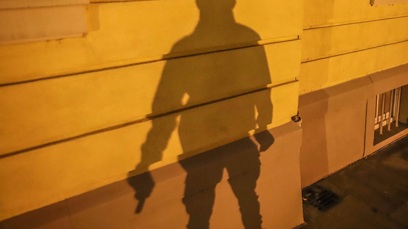 Der Schatten eines Mannes mit Waffe ist zu sehen (Symbolbild): In Hagen haben zwei Männer ein Geschäft mit einer Waffe überfallen.