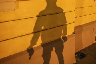 Der Schatten eines Mannes mit Waffe ist zu sehen (Symbolbild): In Hagen haben zwei Männer ein Geschäft mit einer Waffe überfallen.