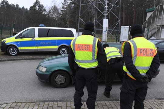 Polizisten kontrollieren ein Fahrzeug vor einem Grenzübergang nach Polen.