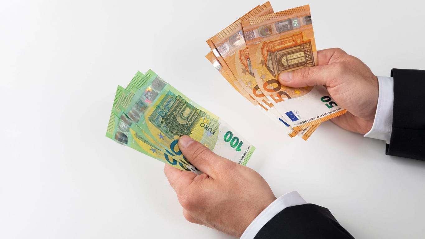 Zwei Hände mit 50 und 100 Euro Geldscheinen (Symbolbild): Eine Künstlerin hat einen Duft kreiert, der nach Banknoten riechen soll.