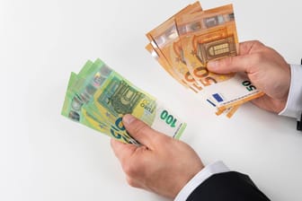Zwei Hände mit 50 und 100 Euro Geldscheinen (Symbolbild): Eine Künstlerin hat einen Duft kreiert, der nach Banknoten riechen soll.