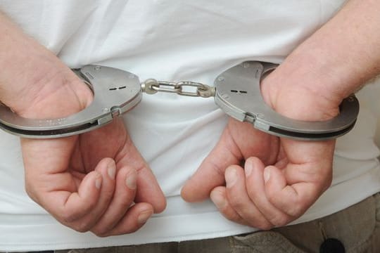 Zwei männliche Hände sind in Polizeihandschellen gefesselt (Symbolbild): In Hessen wird ein 16-Jähriger verdächtigt, einen jungen Mann getötet zu haben.