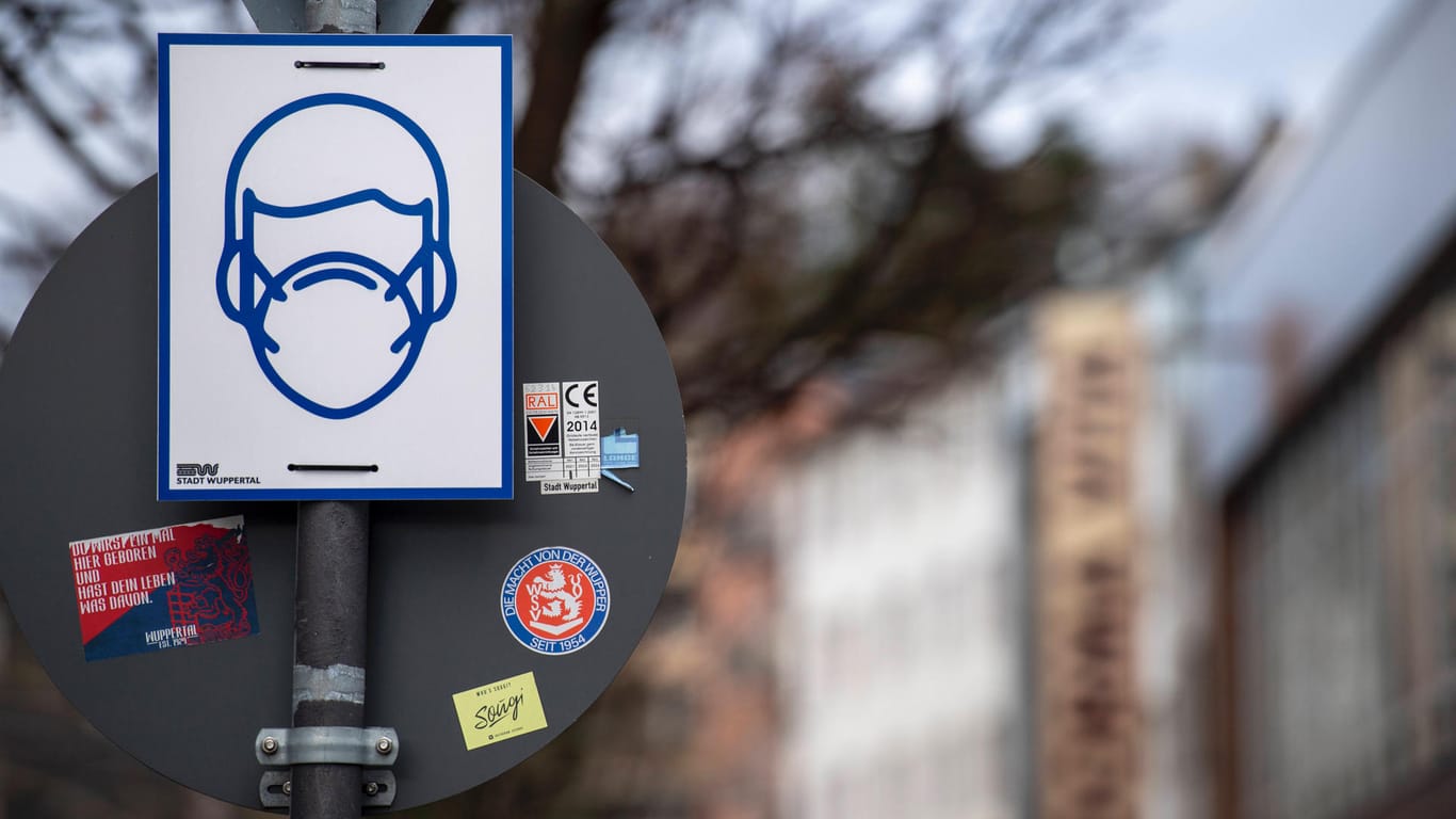 Ein Schild weist auf die Maskenpflicht in der Fußgängerzone von Wuppertal hin (Archivbild): In öffentlichen Verkehrsmitteln müssen ab Montag medizinische Masken getragen werden.