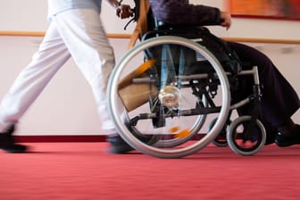 Medizinisches Personal schiebt einen Rollstuhlfahrer: Einige Menschen mit Behinderung werden in der Impf-Priorisierung nicht berücksichtigt (Symbolbild).