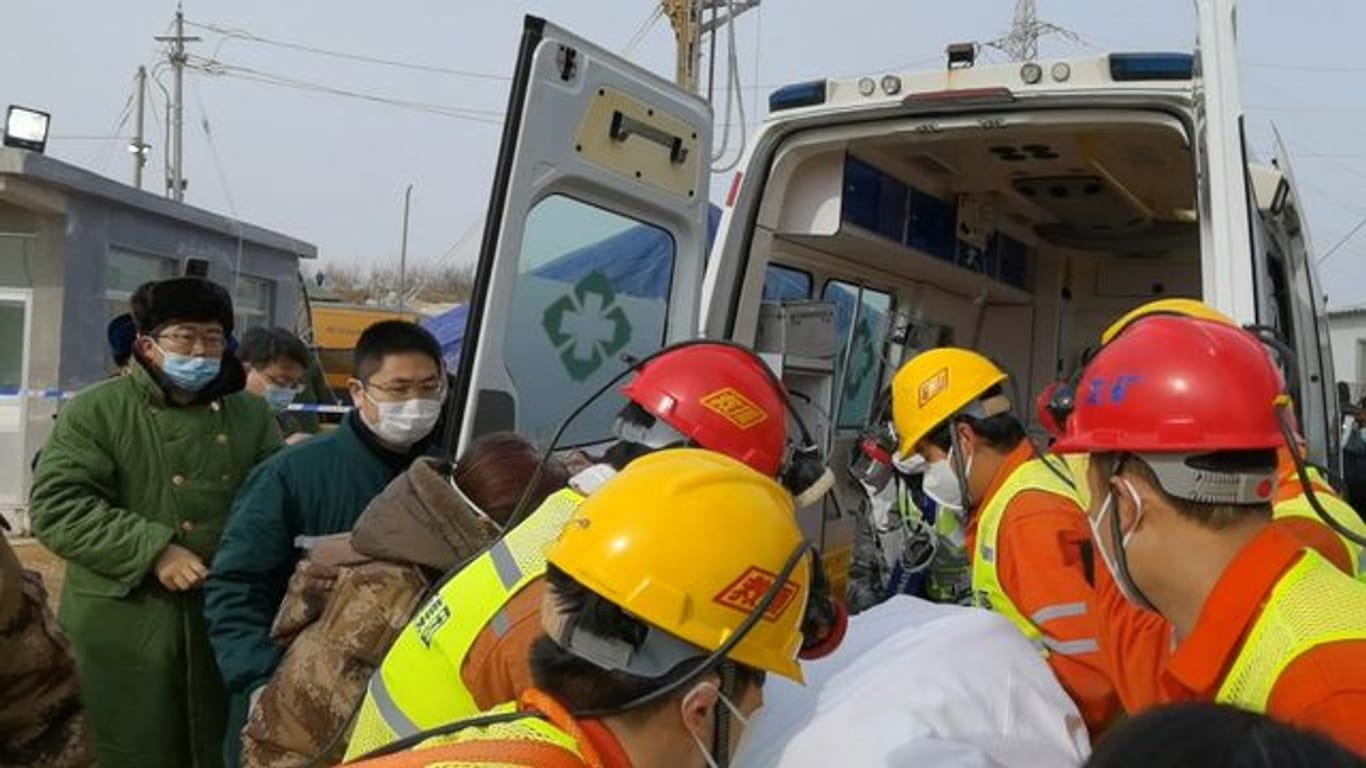 Retter tragen einen Bergarbeiter zu einem Krankenwagen.