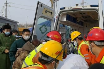 Retter tragen einen Bergarbeiter zu einem Krankenwagen.