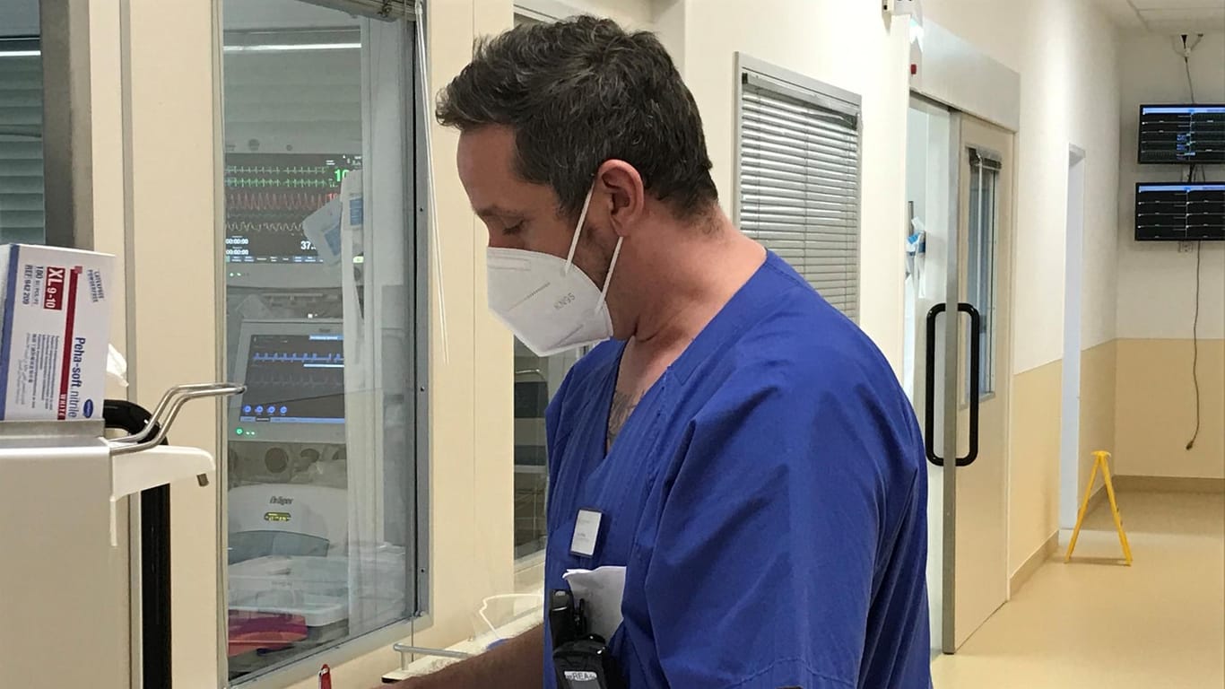 Mühlan mit Maske im Gang seiner Station: der Intensivpfleger bei der Vorbereitung zur Aufnahme eins neuen Patienten.