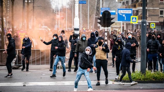 Demonstranten werfen auf einer Straße in Eindhoven mit Steinen.