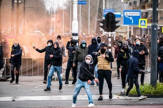 Demonstranten werfen auf einer Straße in Eindhoven mit Steinen.