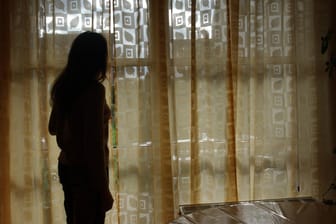 Eine Frau schaut aus einem Fenster nach draußen (Symbolbild): Die meist weiblichen Opfer leiden oft ein Leben lang unter den Folgen des Stalkings.
