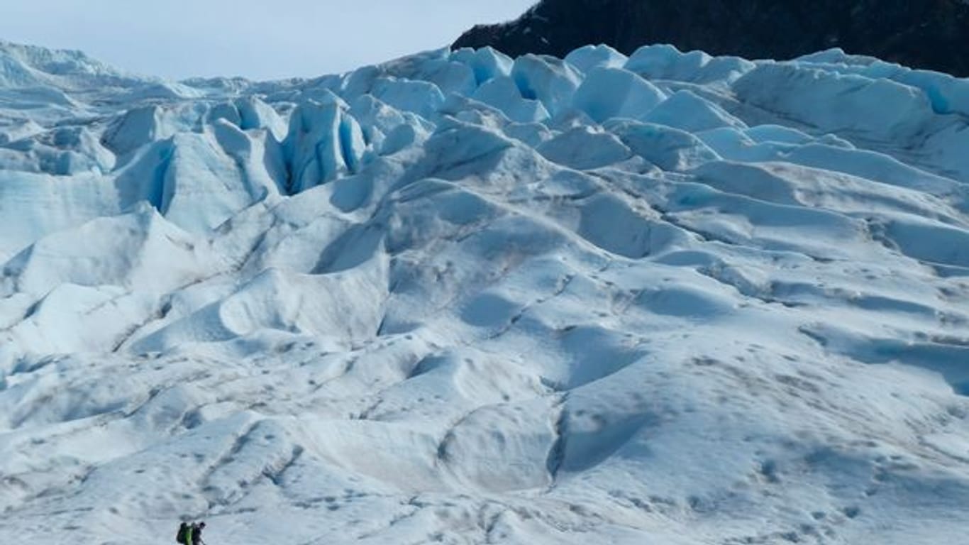 Zwei Menschen wandern auf einem Gletscher in Alaska.