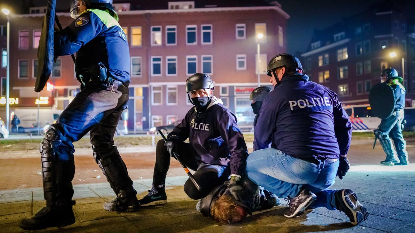 Ein Mann wird nach einer Konfrontation in Rotterdam von Polizisten am Boden festgehalten. Bei den Unruhen wurden Polizisten mit Steinen und Feuerwerkskörpern beworfen.