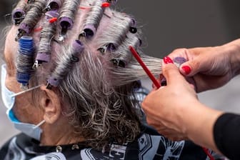 Einer Kundin werden in einem Friseursalon die Haare frisiert