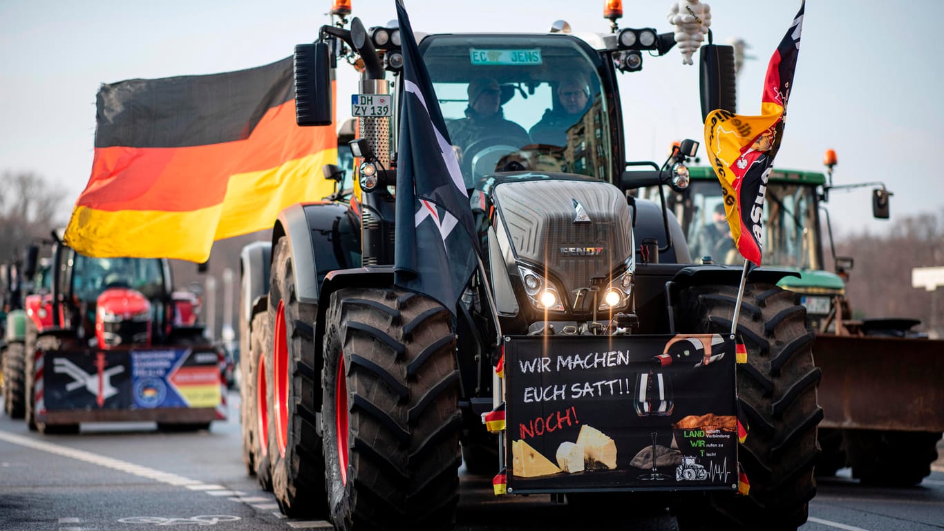 An einem Traktor hängt ein Schild mit der Aufschrift "Wir machen euch satt!! Noch!": Die Landwirte demonstrieren für höhere Preise für Agrarprodukte und weniger Regulierung.