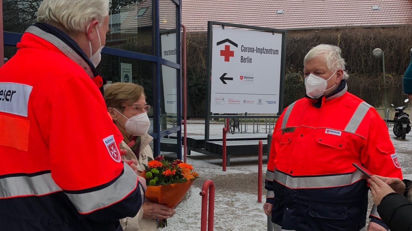 Erste Impflinge: Die 91-jährige Dame, die als erste Geimpfte am Eröffnungstag das Impfzentrum verließ, freute sich über die Blumen und den freundlichen Empfang durch Henric Maes, Diözesangeschäftsführer der Berliner Malteser sowie Diözesanleiter Dr. Jörg Frank von Fürstenwerth.