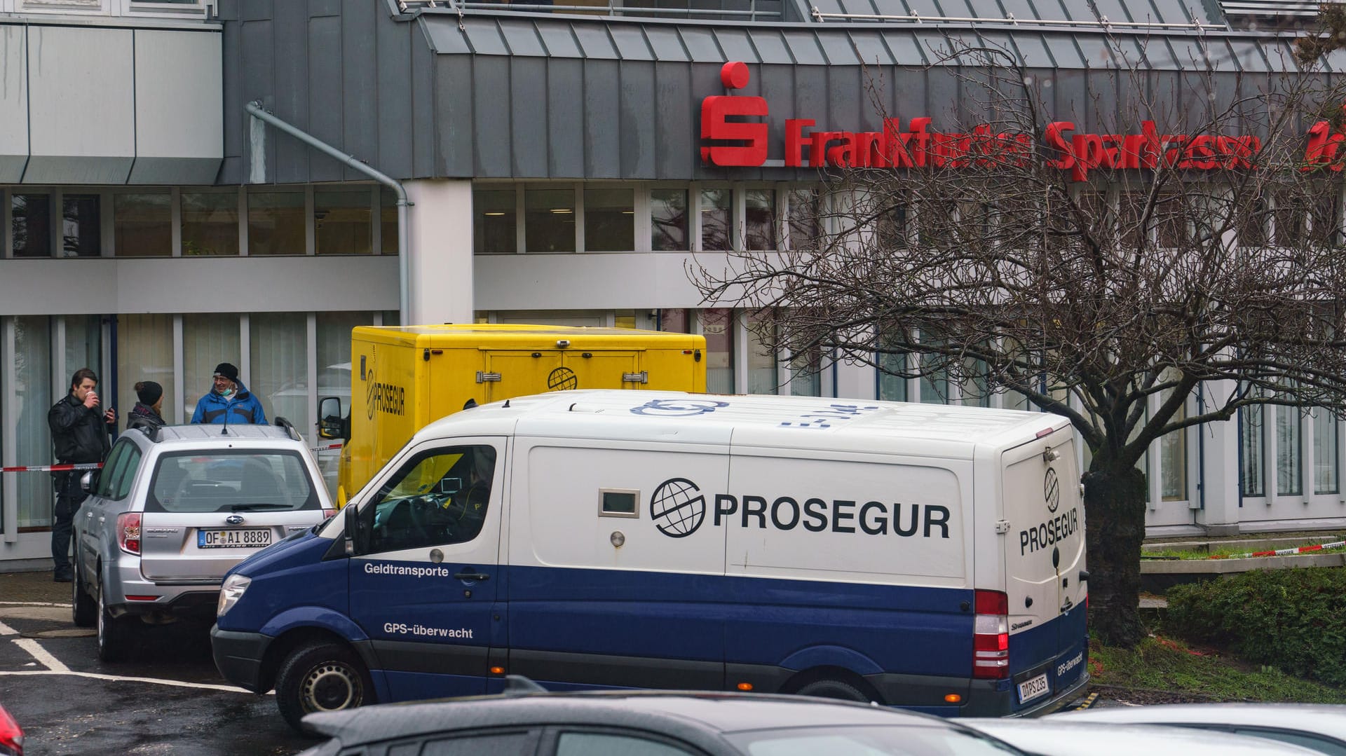 Zwei Geldtransporter stehen vor der Sparkassenfiliale im Stadtteil Bergen, um die Fracht in das vorne stehende Fahrzeug umzuladen: Nach einem Überfall auf den gelben Geldtransporter (hinten) sind mehrere Bewaffnete noch auf der Flucht. Zwei Geldtransporter stehen vor der Sparkassenfiliale im Stadtteil Bergen, um die Fracht in das vorne stehende Fahrzeug umzuladen: Nach einem Überfall auf den gelben Geldtransporter (hinten) sind mehrere Bewaffnete noch auf der Flucht.