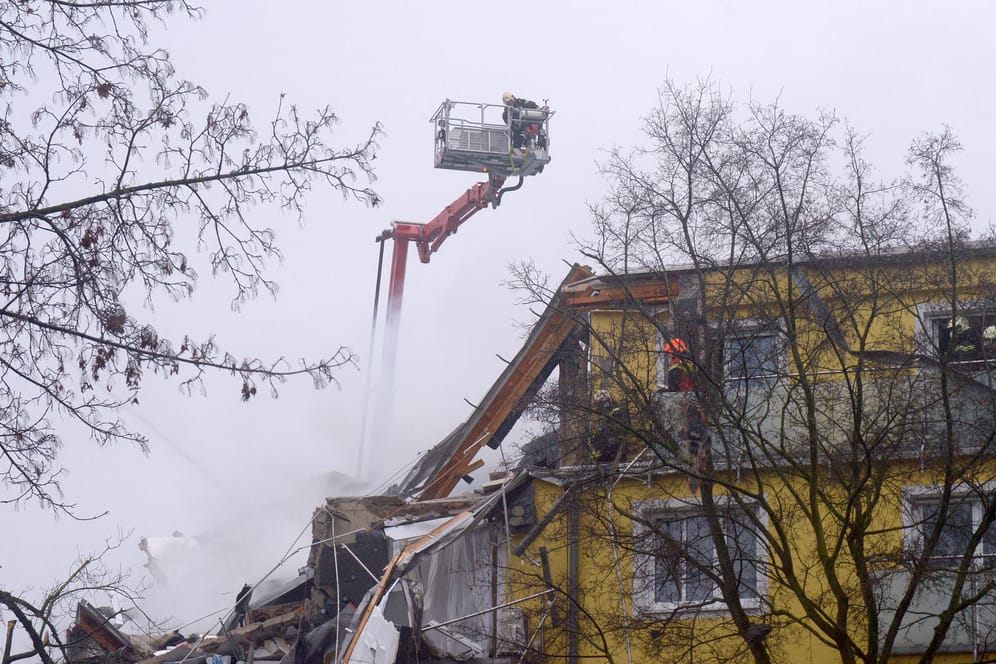 Feuerwehrleute stehen während Löscharbeiten nach einer Explosion auf der Leiter eines Löschzugs.