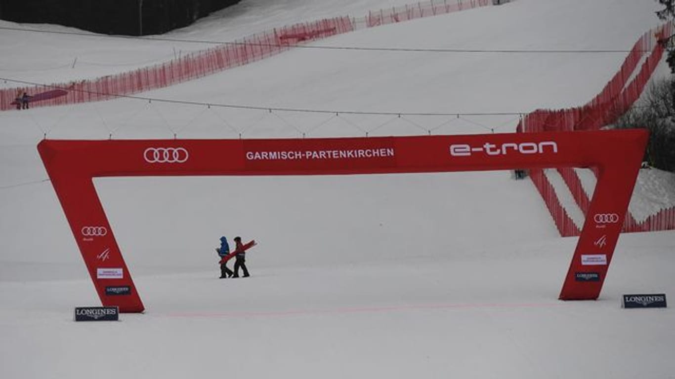 Zwei Helfer gehen in Garmisch hinter dem Zielbogen vorbei.