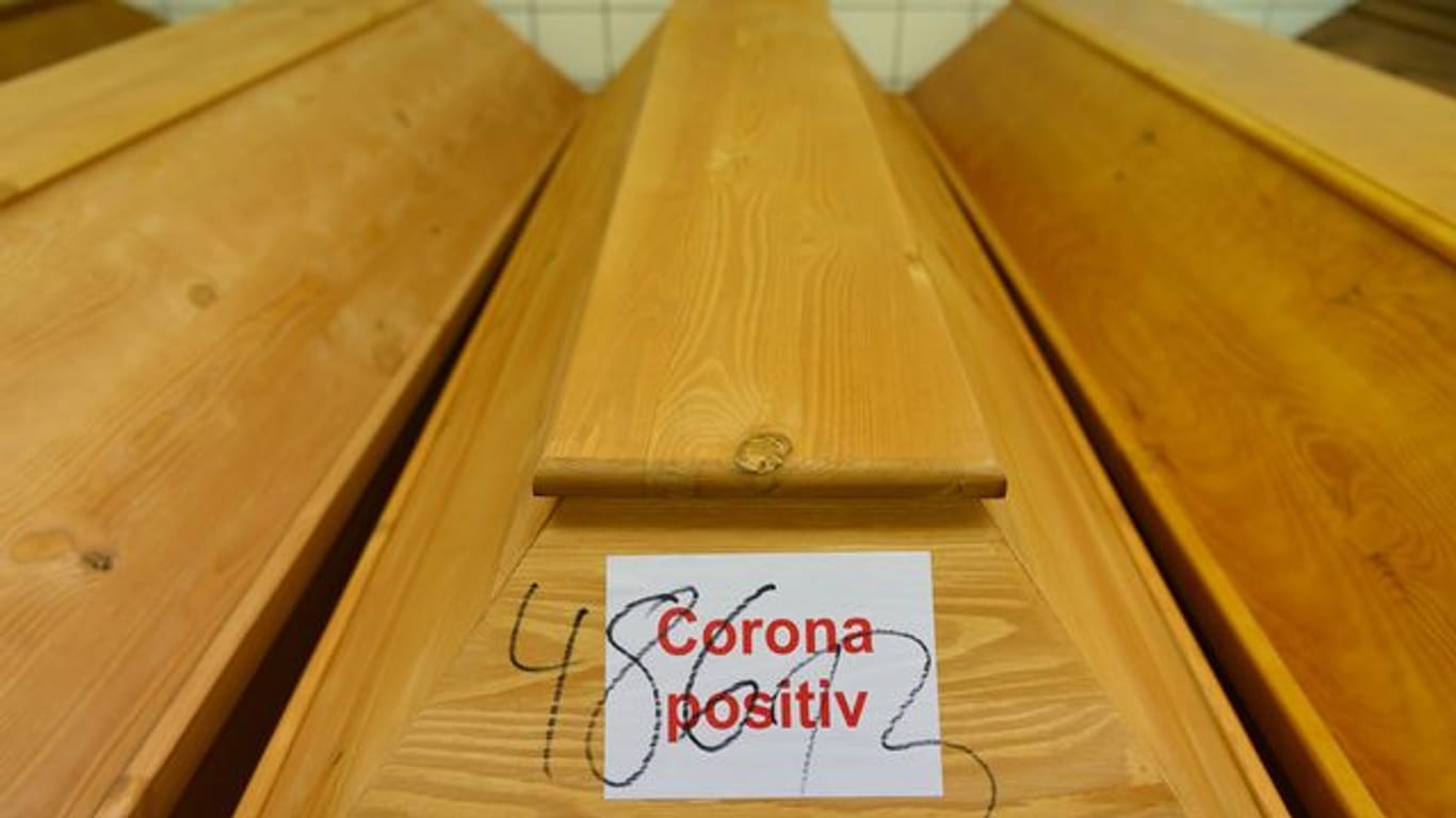 "Corona positiv" steht auf einem Sarg mit einem Verstorbenen, der an oder mit dem Coronavirus gestorben ist.