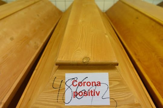 "Corona positiv" steht auf einem Sarg mit einem Verstorbenen, der an oder mit dem Coronavirus gestorben ist.