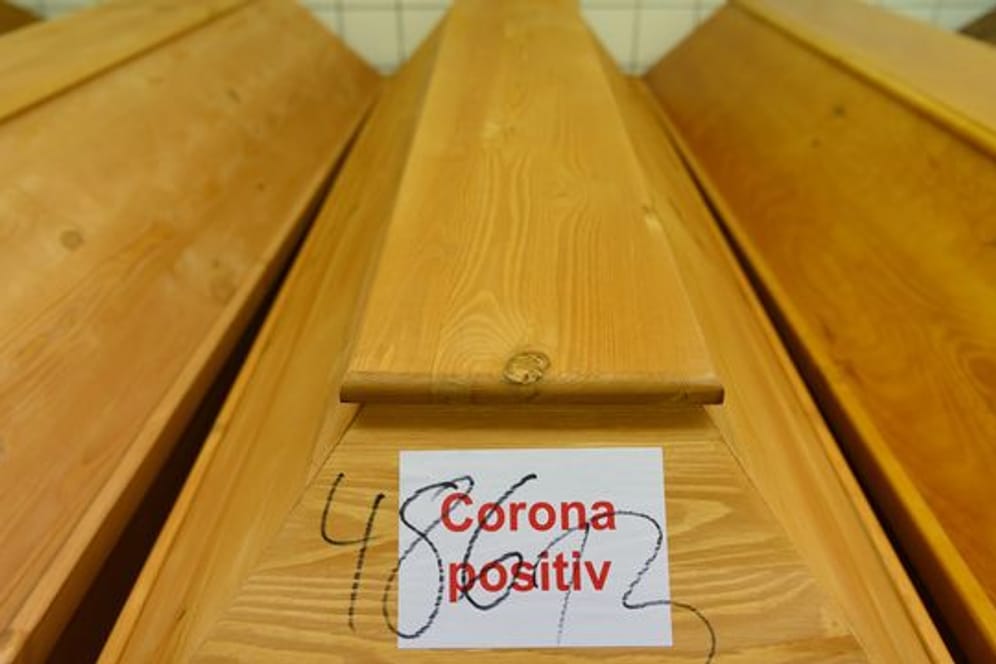 "Corona positiv" steht auf einem Sarg mit einem Verstorbenen, der an oder mit dem Coronavirus gestorben ist.