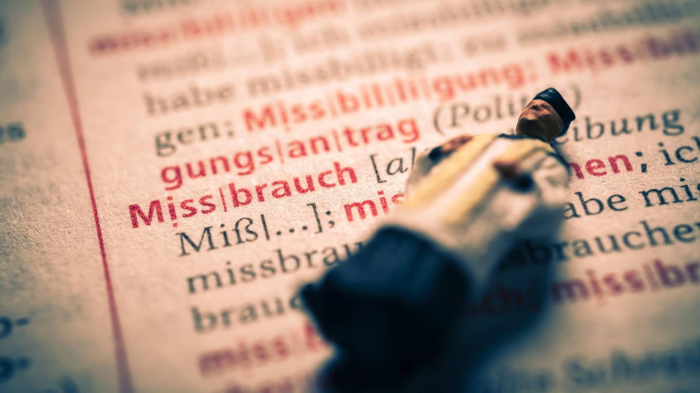 Miniaturfigur eines Priesters in einem Wörterbuch mit dem Wort Missbrauch: In Berlin ist ein Gutachten zum Missbrauch in der Kirche vorgestellt worden.