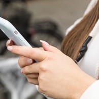 Eine Frau mit Smartphone: Die Berliner Polizei warnt vor einer gefährlichen SMS.